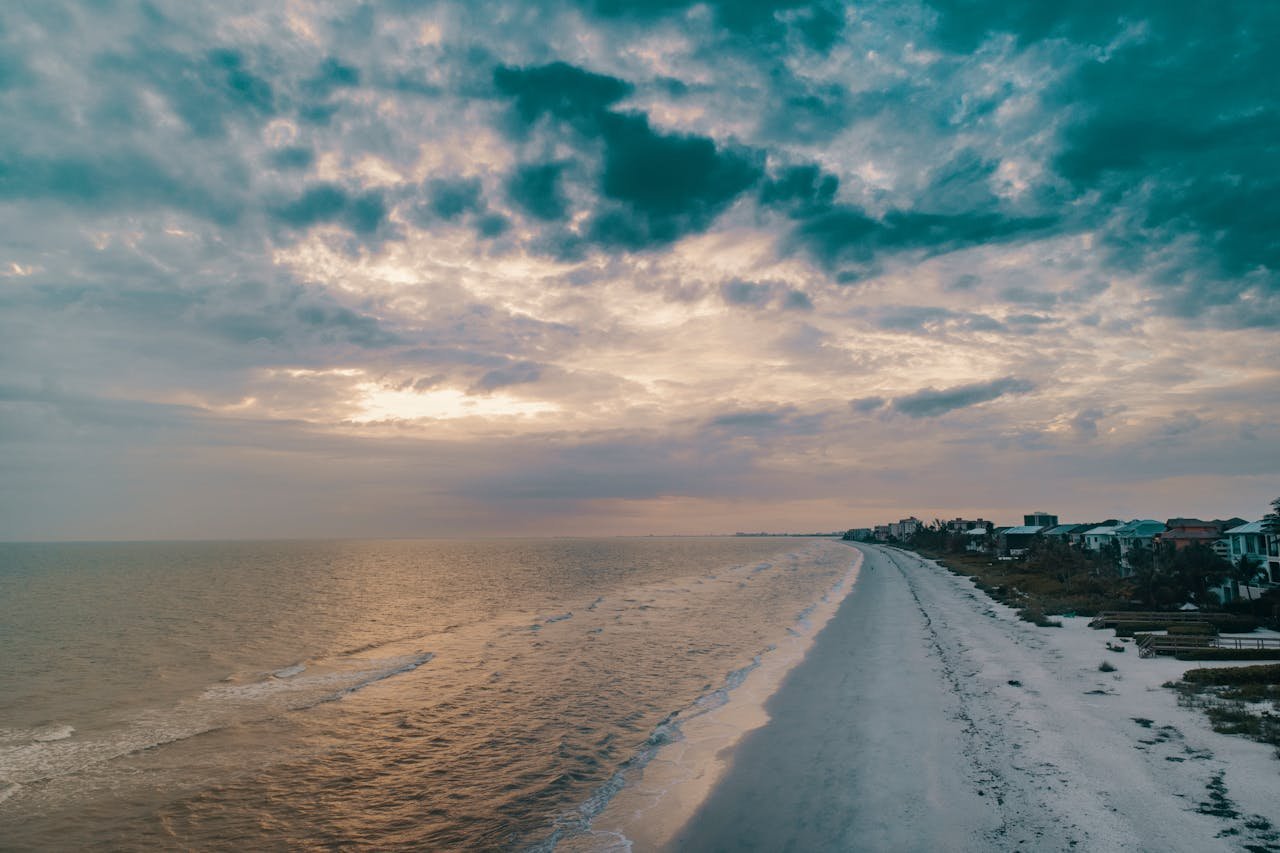 Breathtaking beach sunset with dramatic clouds and serene water, perfect for travel dreams.
